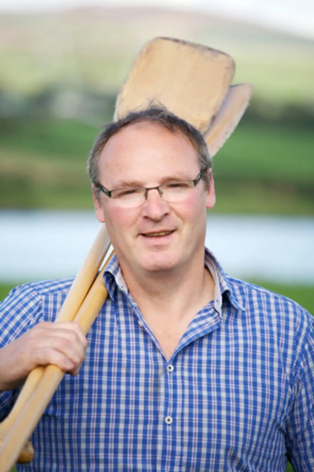 Denis, owner of Blackwater Boating, holding two canoe paddles by the river
