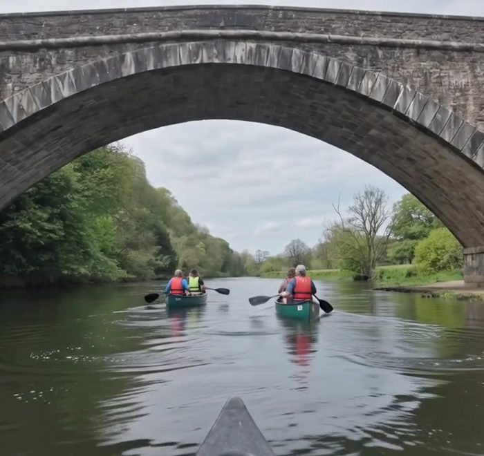 Canoes gliding under the stone bridge on the Blackwater